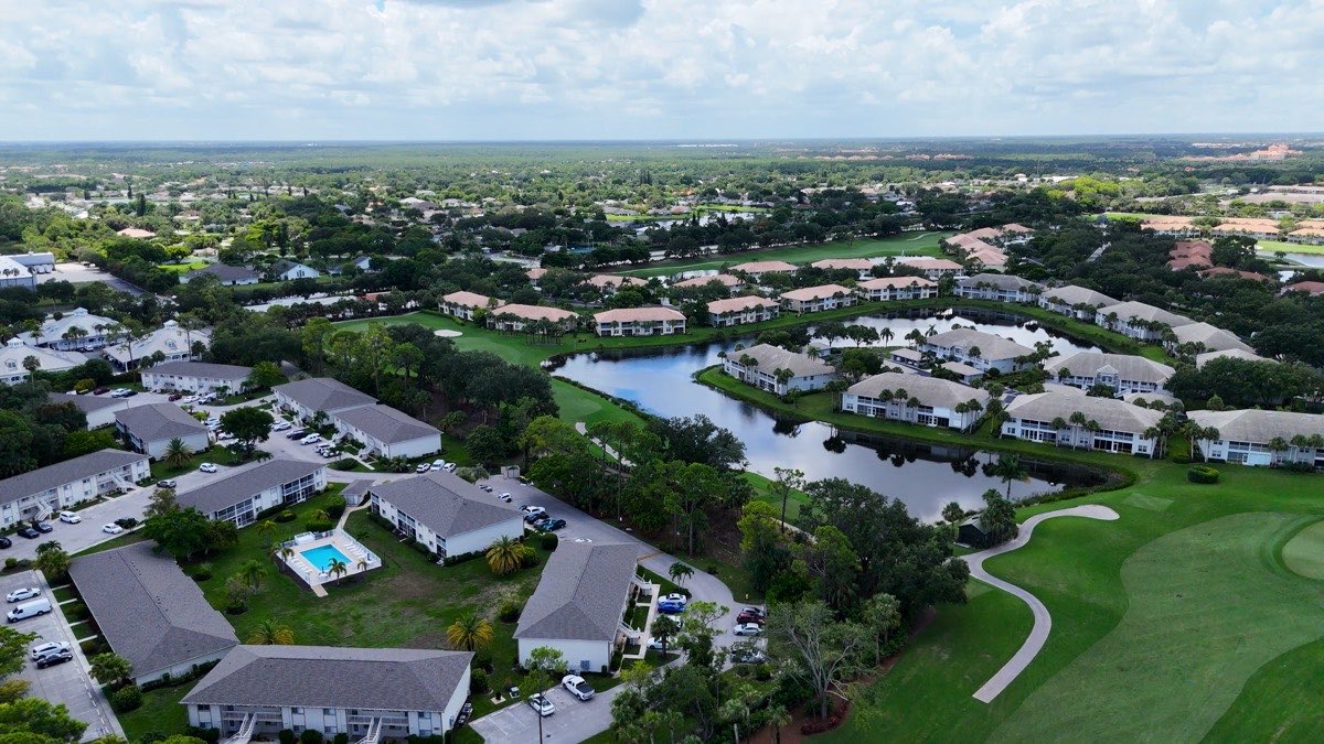 Aerial drone view of a residential community with homes, a pond, and a golf course, the kind of service area a local business covers